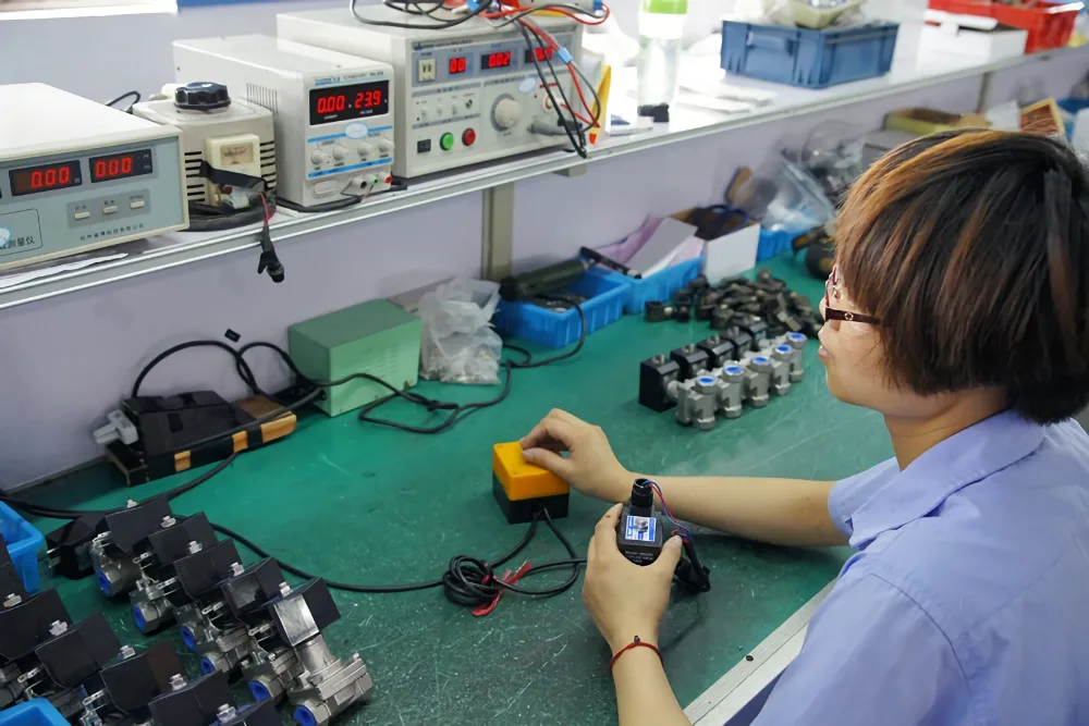 Technician testing solenoid valve coils at a test station